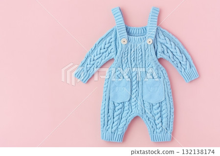 Baby blue knitted onesie on pink background. Fashion newborn clothes. Flat lay top view. Wool kid soft clothing. Infant trendy bodysuit made of organic eco cotton. Children wardrobe. Baby garment 132138174