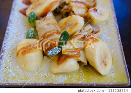Crepes bananas caramel Crepes stuffed with chocolate spread and banana on white plate. Thin pancakes, blini. Sweet dessert. 132138514