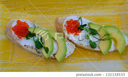 red caviar avocado cheese Toast with salty salmon, trout slices, avocado and red caviar. black background. top view. 132138533