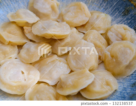 Homemade meat dumplings pelmeni with sour cream and herbs. Dumplings, filled with meat, ravioli, top view with space for your text. 132138537