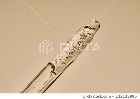 The texture of the serum flowing out of the pipette on a beige background. 132138990