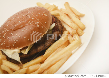 Hamburger with meat and vegetables and French fries. Fast food. Hamburger on a plate. 132139082