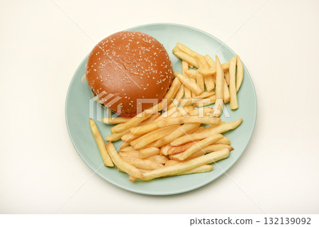 Hamburger with meat and vegetables and French fries. Fast food. Hamburger on a plate. 132139092