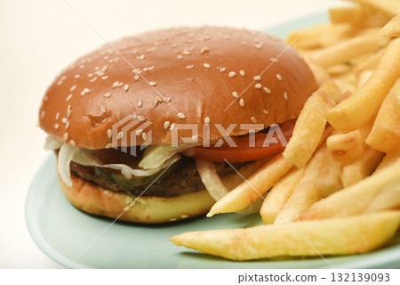 Hamburger with meat and vegetables and French fries. Fast food. Hamburger on a plate. 132139093