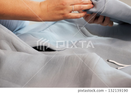 Woman reviewing a blue hoodie 132139190