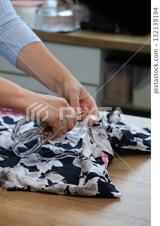 Woman reviewing a light dress Cutting the label Woman reviewing a light dress Cutting the label 132139194