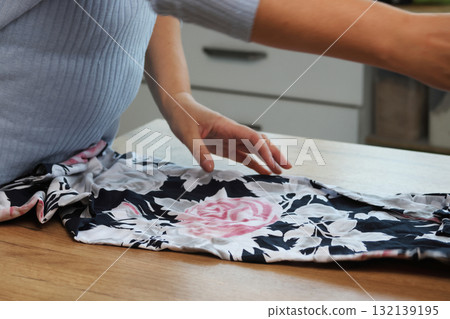 Woman reviewing a light dress Spreading it out on a table Woman reviewing a light dress Spreading it out on a table 132139195