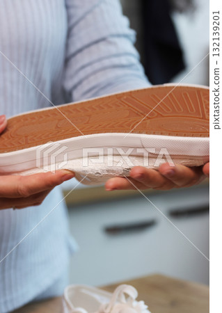 Woman checking the sole quality of white sneakers Sneakers with lace-up tops Woman checking the sole quality of white sneakers Sneakers with lace-up tops 132139201