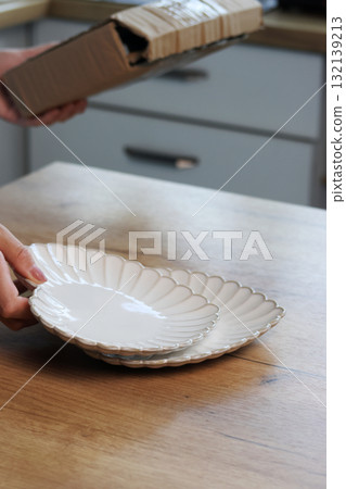 Woman unboxing and reviewing porcelain plates Heart-shaped plates Woman unboxing and reviewing porcelain plates Heart-shaped plates 132139213
