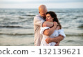 Couple embraces on a calm beach at sunset sharing a tender moment and enjoying the serene ocean view 132139621