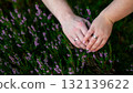 Couple's hands carefully gardening together in a lush green environment with pink flowers in the background 132139622
