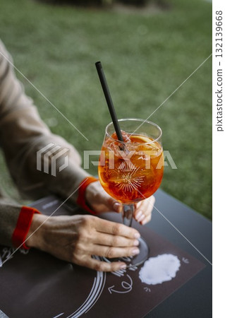 Woman Holding Aperol Spritz at Outdoor Table Woman Holding Aperol Spritz at Outdoor Table 132139668