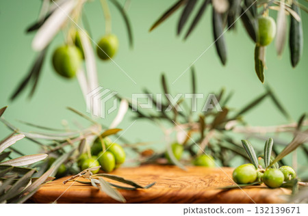 Fresh green olives and olive branches on wooden surface with green background Fresh green olives and olive branches on wooden surface with green background 132139671