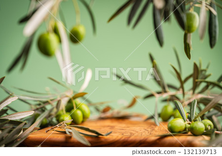 Fresh green olives and olive branches on wooden surface with green background 132139713