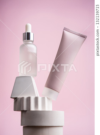 Facial serum and peeling mask on geometric display with pink background Facial serum and peeling mask on geometric display with pink background 132139715