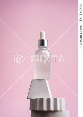 Glass bottle of peptide facial serum on geometric display with pink background Glass bottle of peptide facial serum on geometric display with pink background 132139728