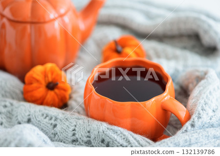 Autumnal tea set with pumpkin decor on a cozy knitted blanket. 132139786