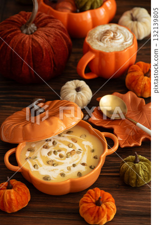 Autumnal lunch with pumpkin soup in a pumpkin-shaped bowl, pumpkin latte, croutons and festive decor on dark wooden table Autumnal lunch with pumpkin soup in a pumpkin-shaped bowl, pumpkin latte, croutons and festive decor on dark wooden table 132139805