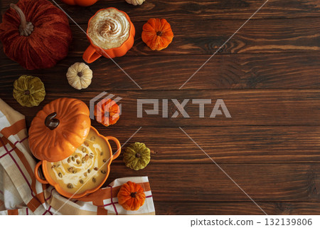 Autumnal lunch with pumpkin soup in a pumpkin-shaped bowl, pumpkin latte, croutons and festive decor on dark wooden table. Top view. Copy space 132139806