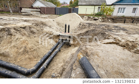 Construction site showing buried pipes and excavation work in a residential area during daylight 132139832