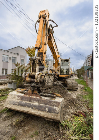 Construction equipment digging near residential buildings on an overcast day in the city 132139835
