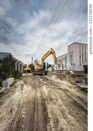 Construction site with heavy machinery operating on a cloudy day in a residential area Construction site with heavy machinery operating on a cloudy day in a residential area 132139836