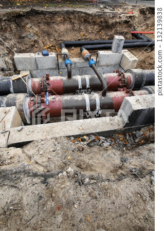 Underground utility maintenance involving pipes and connections in a construction site during autumn season Underground utility maintenance involving pipes and connections in a construction site during autumn season 132139838