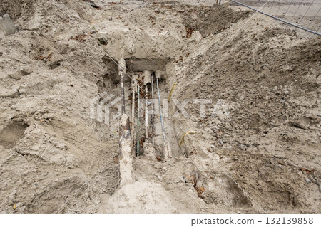Construction site with exposed underground utilities and freshly dug soil during infrastructure work 132139858
