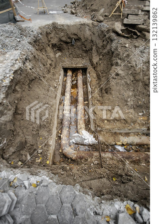 Construction site with exposed underground pipes being repaired in a city street during autumn Construction site with exposed underground pipes being repaired in a city street during autumn 132139862