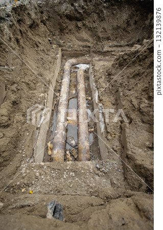 Construction site shows exposed old pipelines in trench during urban infrastructure project in late afternoon light 132139876