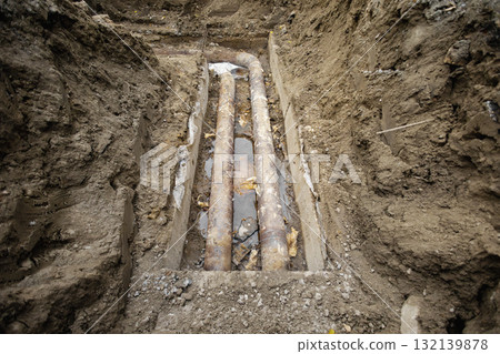 Construction workers uncover old metal pipes during excavation at a construction site in a urban area 132139878
