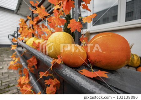 Colorful autumn pumpkins and leaves decorate a railing in a cozy outdoor setting 132139880