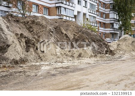 Construction site showing dirt pile near residential buildings during daytime work hours Construction site showing dirt pile near residential buildings during daytime work hours 132139913