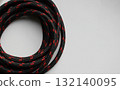 A skein of black rope with red inserts on a white surface with copy space. Round rope wound into a skein stock photo 132140095