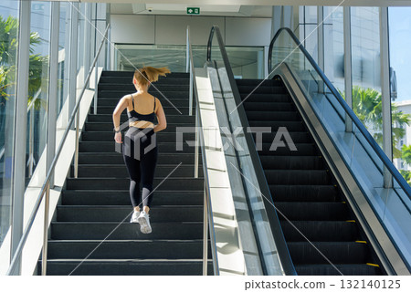 Exercise for fitness, sport woman performs vigorous workout, people running outdoor urban stairs, enjoying bright light, building stamina with challenging daily exercise routine. Exercise for fitness, sport woman performs vigorous workout, people running outdoor urban stairs, enjoying bright light, building stamina with challenging daily exercise routine. 132140125