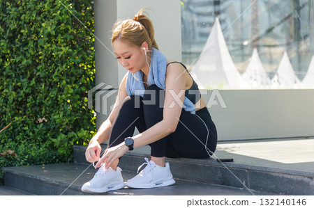 Workout prepares sport woman, feeling fit for outdoor exercise, she ties running shoes ready for active training, next vigorous workout fuels healthy living. 132140146