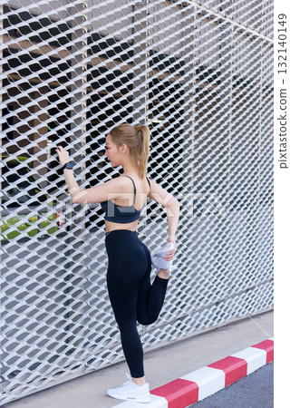 Sport woman exercises outdoor, stretching for intense workout, showing fit body, preparing for sport activity, posing against clean modern architectural background for health. Sport woman exercises outdoor, stretching for intense workout, showing fit body, preparing for sport activity, posing against clean modern architectural background for health. 132140149