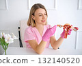 A beautiful young gynecologist in pink gloves talks enthusiastically about the problems of women's health in gynecology, showing an anatomical model of the uterus 132140520