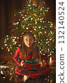 A cheerful laughing girl in the middle of the night curiously opens Christmas presents. 132140524