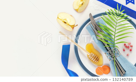 Rosh hashanah, Jewish New Year holiday. Rosh hashanah flat lay with table setting and traditional symbols, apples, honey, carrots and pomegranate on white background with copy space. Jewish holidays 132140789