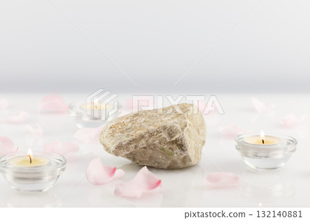 Stone podium with pink rose petals and candles on a white table. Concept scene stage showcase for new product, promotion sale, banner, presentation, cosmetic. Soft image and soft focus style 132140881