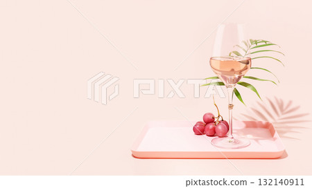 Rose wine. Minimalistic, Summer, holiday composition with glass of rose wine, grapes and palm leaf on a pink tray on pink background with copy space. Self-partnered and self love concept. Summer party 132140911