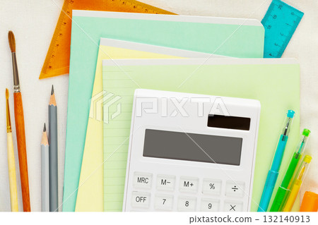 Back to school flat lay with multicolored notebooks, pens, brushes, rulers and calculator on a white textile bag. School supplies. School sale and buying concept. Flat lay, close up 132140913