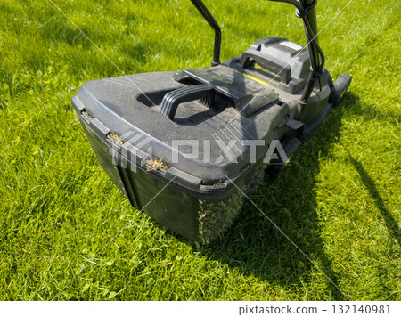 Lawnmower mowing green grass on a sunny day outdoors 132140981