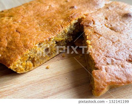 Close-up of sliced homemade pie with golden crust on cutting board. Texture, detail, and visual warmth of home baking and comforting sweetness. 132141199