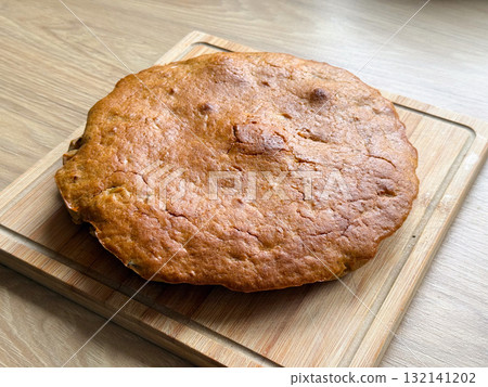 Golden baked homemade pie placed on wooden cutting board. Minimalist aesthetic of rustic food photography and homemade dessert tradition. Golden baked homemade pie placed on wooden cutting board. Minimalist aesthetic of rustic food photography and homemade dessert tradition. 132141202