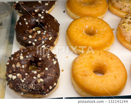 Assorted donuts with chocolate and sugar glaze. Concept of indulgence, sweetness, and variety in modern bakery presentation and everyday culinary joy. Assorted donuts with chocolate and sugar glaze. Concept of indulgence, sweetness, and variety in modern bakery presentation and everyday culinary joy. 132141244