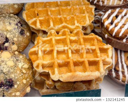 Golden waffles in bakery showcase. Reflection of breakfast tradition, crisp texture, and culinary delight associated with sweetness and comforting flavor. 132141245