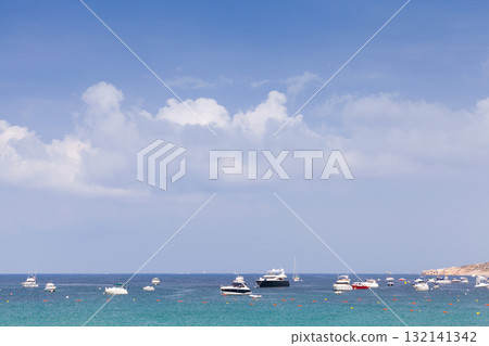 A serene coastal view featuring multiple small boats anchored near a quiet shoreline A serene coastal view featuring multiple small boats anchored near a quiet shoreline 132141342