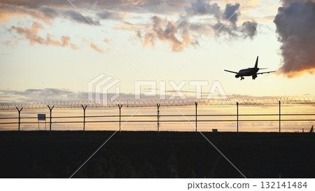 Airplane landing during sunset, silhouette of aircraft in beautiful evening sky 132141484